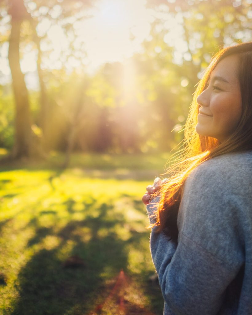 Portrait image of a beautiful asian woman standing among nature in the park before sunset